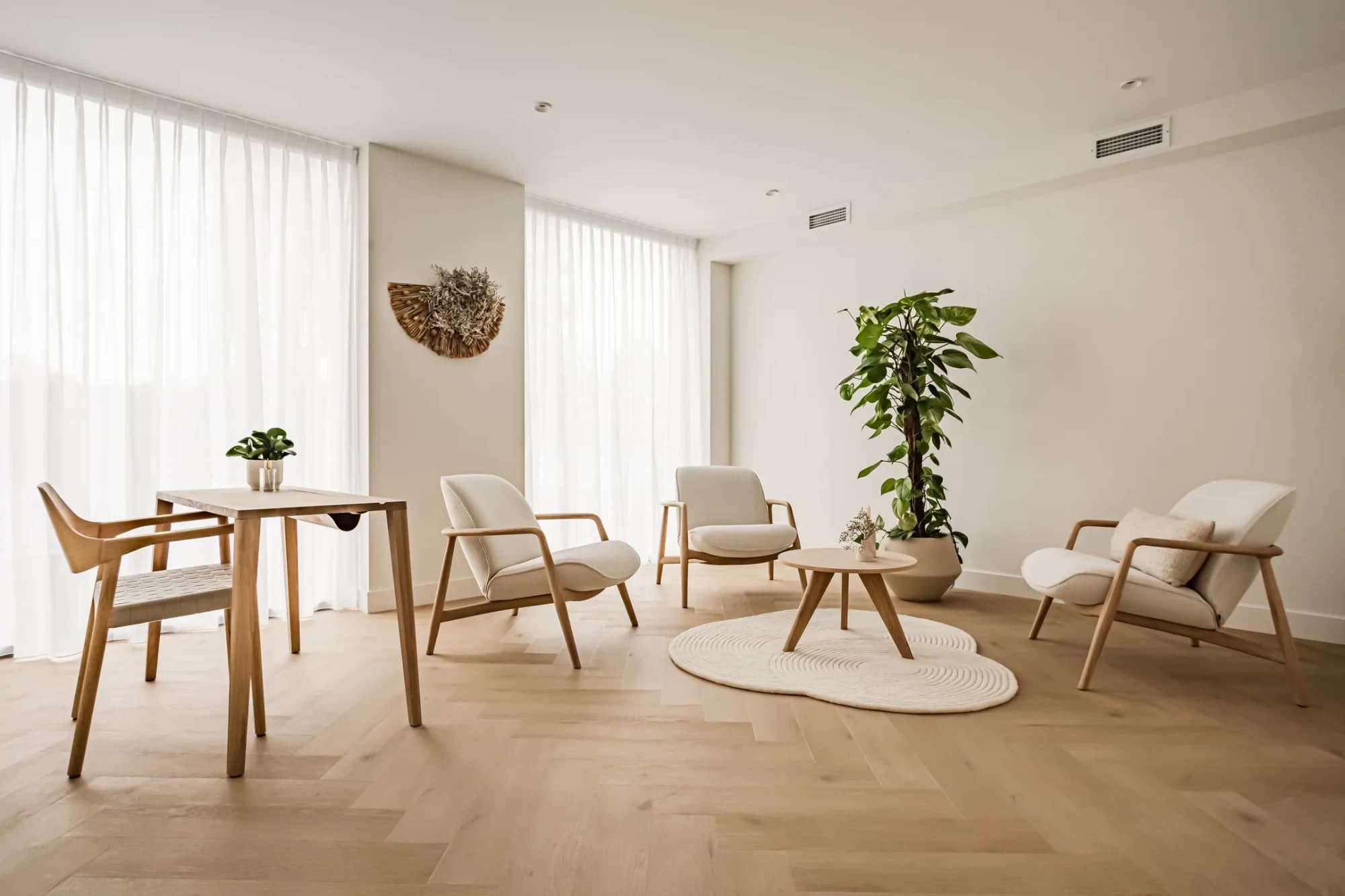 Ruime therapiekamer met zithoek, tafel en grote planten