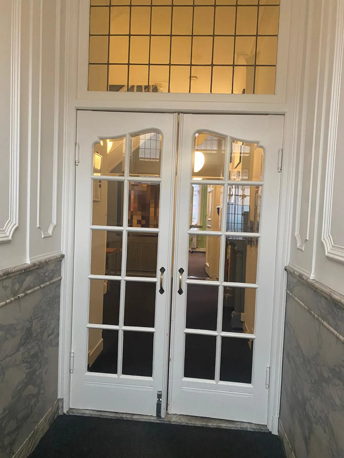 Stijlvolle entree met openslaande deuren en marmeren lambrisering