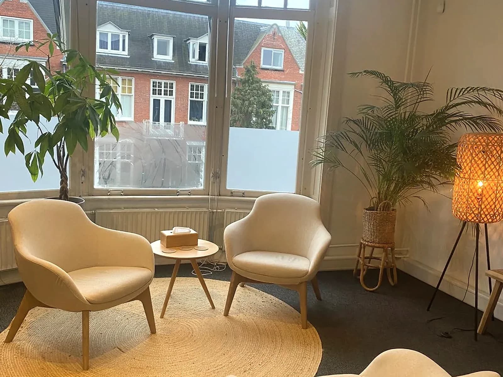 Sfeervolle therapiekamer met erkerraam, comfortabele stoelen en planten