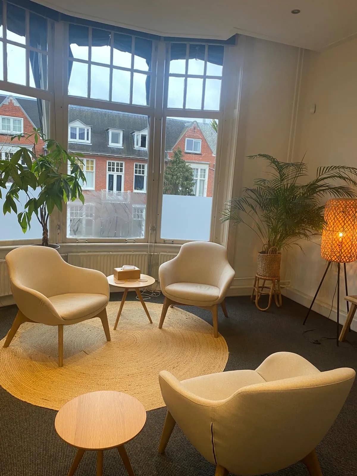 Sfeervolle therapiekamer met erkerraam, comfortabele stoelen en planten